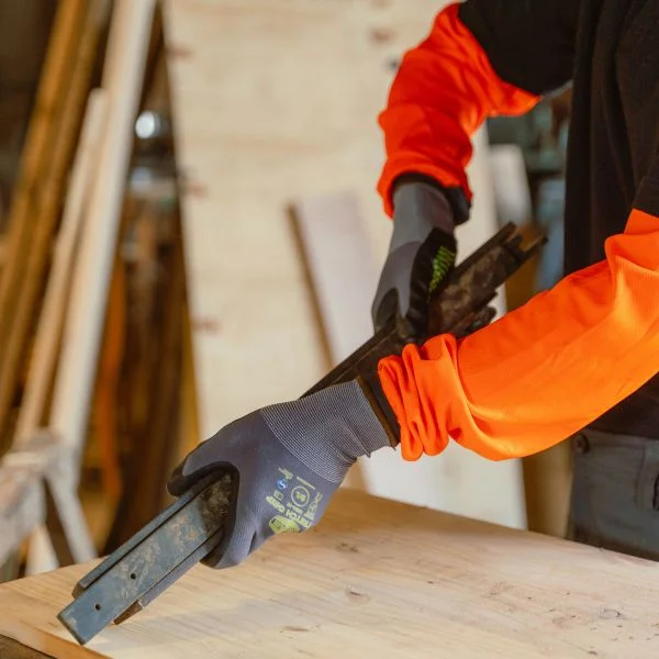 Solidur GAT01 grip gloves with safety stretch material - being worn by a forestry worker holding a metal bar - Lifestyle Product Image